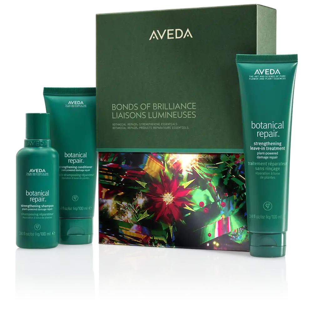 Aveda Bonds of Brilliance set with three green bottles of Botanical Repair shampoo, conditioner, and leave-in treatment—your essential winter hair care trio—displayed next to a colorful boxed package. - Trios Aveda Salon | Fort Collins, CO