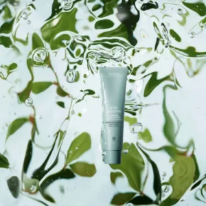 A tube of Aveda Scalp Solutions, perfect for spring hair and skin prep, is suspended in clear water with green leaves in the background. - Trios Aveda Salon | Fort Collins, CO