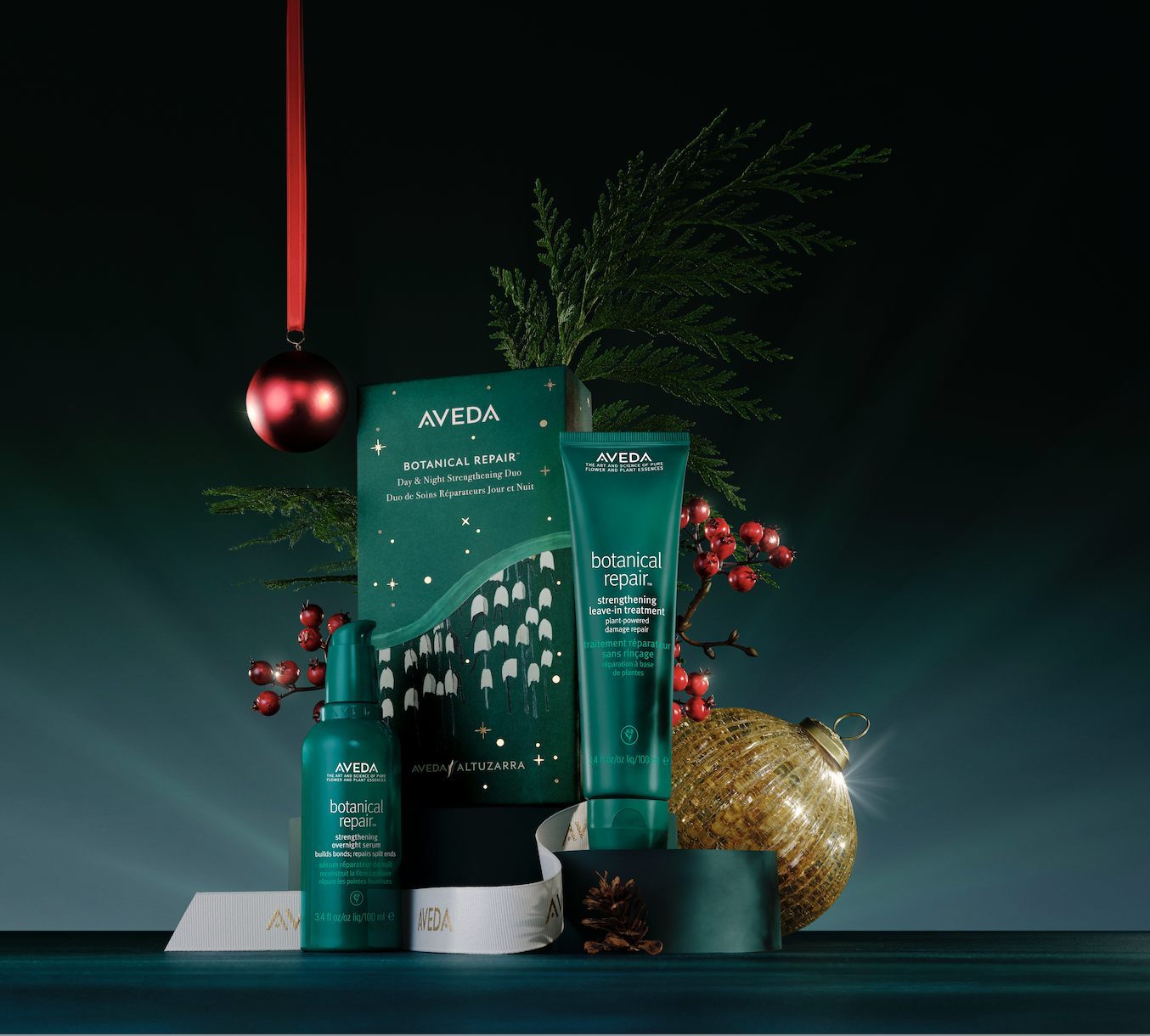 Aveda Botanical Repair gift set with festive decorations, including red berries, ornaments, and greenery on a dark background. - Trios Aveda Salon | Fort Collins, CO