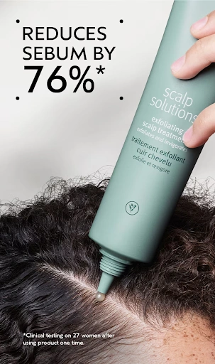 A person applies a liquid scalp exfoliant to their scalp; text on the image states “Reduces sebum by 76%*”. - Trios Aveda Salon | Fort Collins, CO